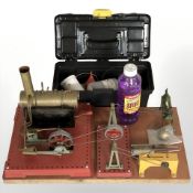 A Mamod live steam engine on plinth and a small plastic toolbox containing associated items.