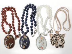 A decorative leopard pendant on chain together with three contrasting pendant and beaded necklaces.