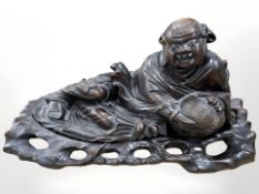 A 19th century Chinese carved hardwood figure of a reclining man with wicker basket, length 40 cm.