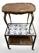 A two tier mahogany trolley with inset delft tiles,