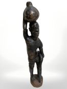 An African wooden statue of a man carrying a pot above his head, height 90 cm.