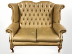 A Chesterfield tan leather two seater wingback settee, 140 cm W x 87 cm D x 106 cm H.