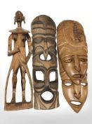An eastern carved hardwood figure and three masks.