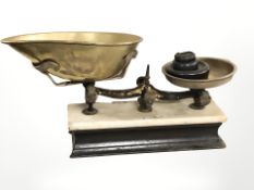 A set of brass pan scales with weights on marble topped plinth,