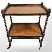 An Edwardian oak barley twist two tier trolley, width 64 cm.