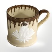 A 19th century yellow and slip glazed mug with applied white thistles, height 10.5 cm.