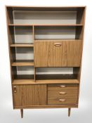 A teak effect open bookcase incorporating a drinks cabinet, with cupboards beneath,