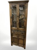 A reproduction carved oak corner cabinet with leaded glass doors,