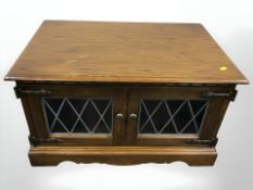 A reproduction oak low cabinet with leaded glass doors,