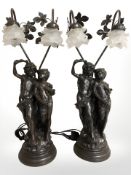 A pair of bronzed resin figural table lamps with frosted glass petal shades, height 76 cm.