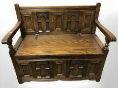A reproduction oak storage settle, 98 cm W x 50 cm D x 85 cm H.