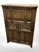 A reproduction oak linen fold drinks cabinet, 76 cm W x 37 cm D x 110 cm H.