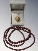A polished red stone graduated bead necklace and a brooch, signed N S Meyer, New York,