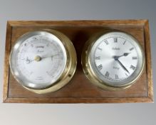 A brass cased barometer and eight day timepiece mounted on board, width 26 cm.