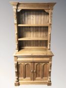 A modern pine bookcase fitted cupboards and drawers beneath,