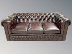 A Chesterfield oxblood buttoned leather three seater club settee,