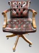 A oxblood buttoned leather captain's style swivel armchair,
