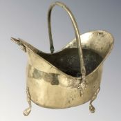A Victorian brass coal helmet on paw feet, length 48 cm.