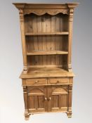 A modern pine bookcase fitted cupboards and drawers beneath,