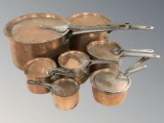 A group of 19th century graduated steel-handled copper saucepans with lids, largest 52 cm long.