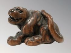 A Japanese carved hardwood netsuke of a recumbent tiger, late-19th century, unsigned, length 4cm.
