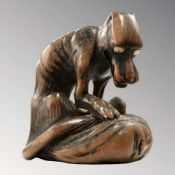 A Japanese Toyomasa School carved hardwood netsuke in the form of a starving wolf standing over a