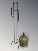 A wrought metal candle stand, height 140 cm, and a glass carboy in metal container.