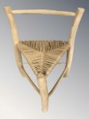 A rustic triangular chair with rush seat.