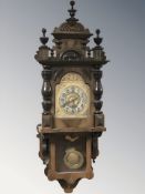 A continental walnut wall clock with pendulum, height 110 cm.