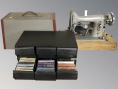 A sewing machine in box and a multi drawer box containing cassette tapes.