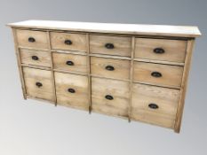 An early 20th century pine twelve drawer sideboard, 202 cm L x 45 cm D x 102 cm H.