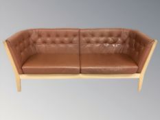 A late 20th century Danish Stouby three seater wooden framed settee with terracotta leather