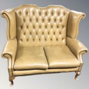 A Chesterfield tan buttoned leather wing backed two seater settee,