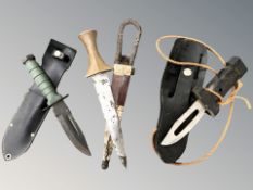 Two diving knives and a further African knife, all in sheathes,
