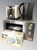 A Bosch microwave together with a toaster, kettle and iron.