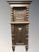 An early 20th century continental carved and stained oak pedestal cabinet,