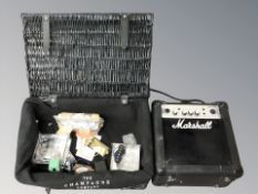 A Marshall MG10CF amplifier and a wicker hamper containing further musical equipment including