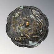 An oriental patinated bronze hand mirror depicting a phoenix, 19th century, diameter 12.