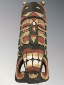A carved and painted wooden Tiki mask, length 51 cm.