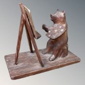 A small Black Forest carved wooden bear, modelled as an artist with easel and palette,