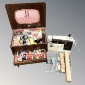 An early 20th century oak sewing box and contents, a Brother electric sewing machine with lead,