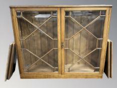 An early 20th century oak and bevelled glass double door book case, with shelved interior,