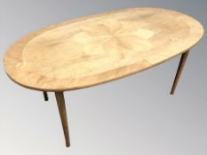An oval teak coffee table, width 130 cm.