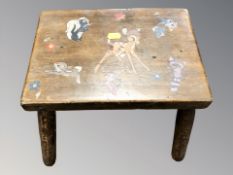 A small mid century oak stool, decorated with Disney characters,