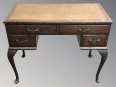 An early 20th century oak four drawer writing desk on cabriole legs,