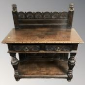 A Victorian carved and stained oak buffet side table fitted with two drawers,