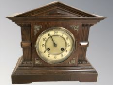 A late Victorian oak mantel clock with brass and enamelled dial striking on a gong, with key,