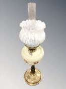 A brass oil lamp with hand painted opaque glass reservoir and marbled shade,