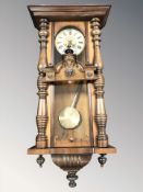 An early 20th century walnut Vienna wall clock with pendulum,
