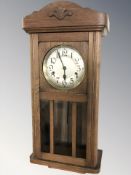 An early 20th century oak eight day wall clock with pendulum,